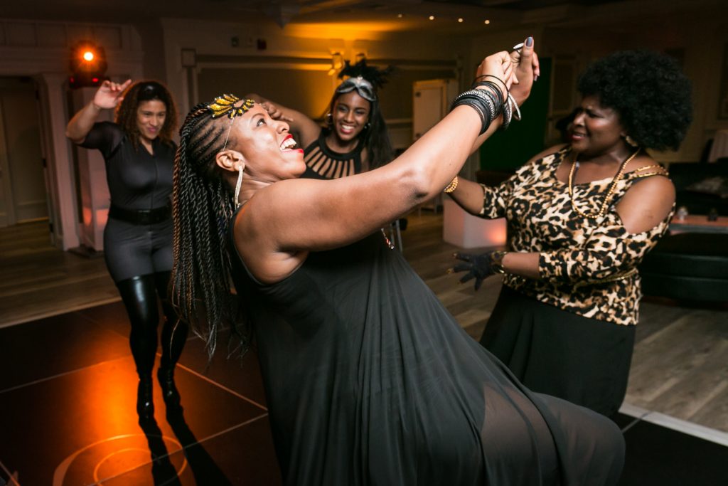 African American woman in black dress dancing for an article on how to plan a Halloween wedding