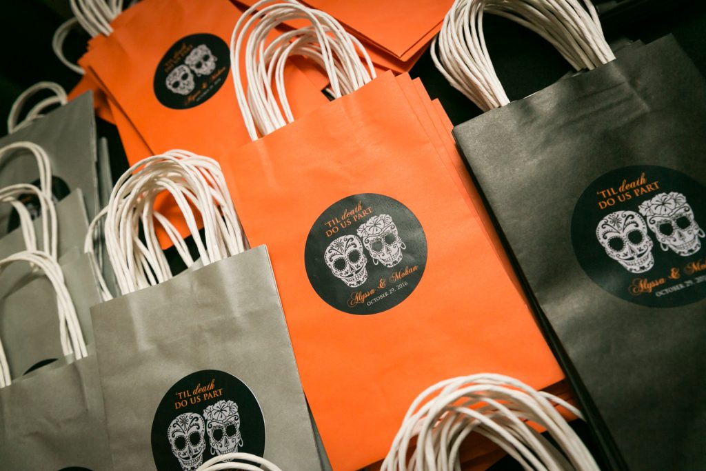Orange, black, and grey bags with personalized tags for a Halloween-themed wedding reception