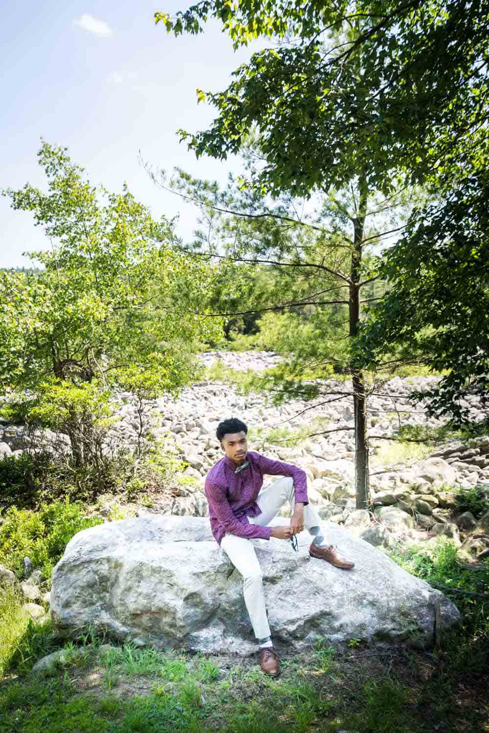 African American young man sitting on rock during a family reunion portrait