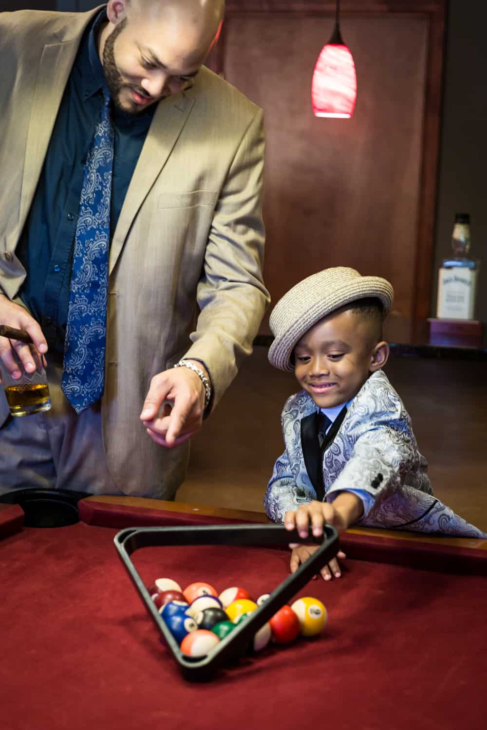 Man helping little boy learn to rack pool balls during a family reunion portrait