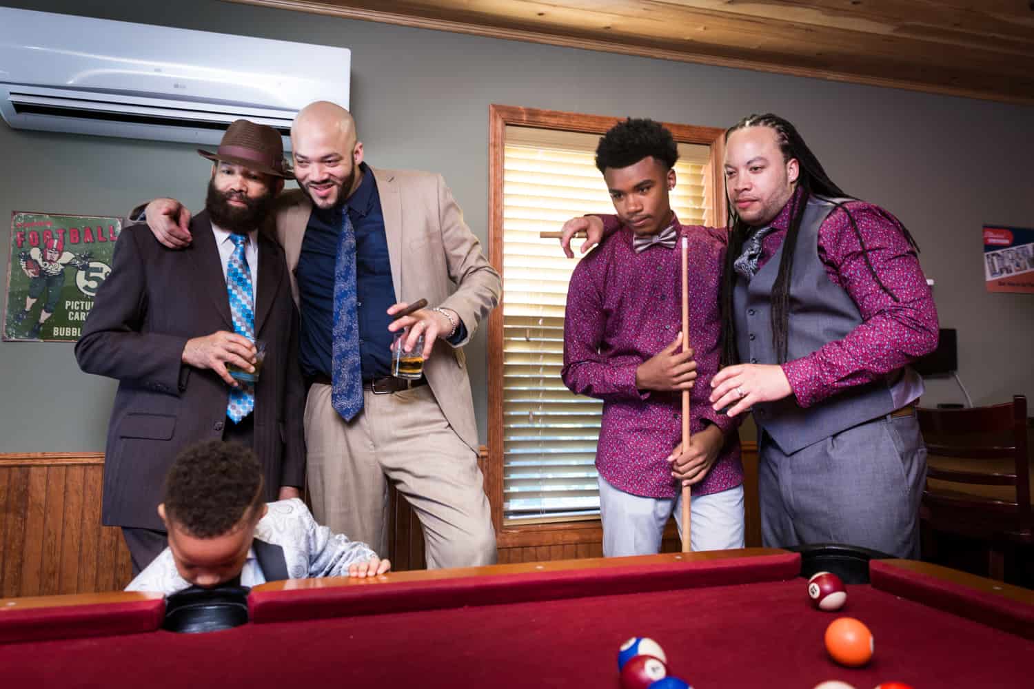 Male family members watching pool table during a family reunion portrait