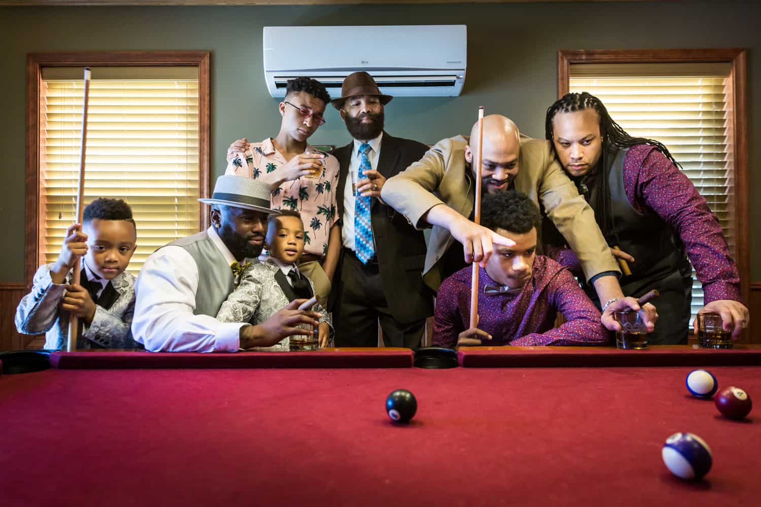 Male family members helping little boys play pool during a family reunion portrait