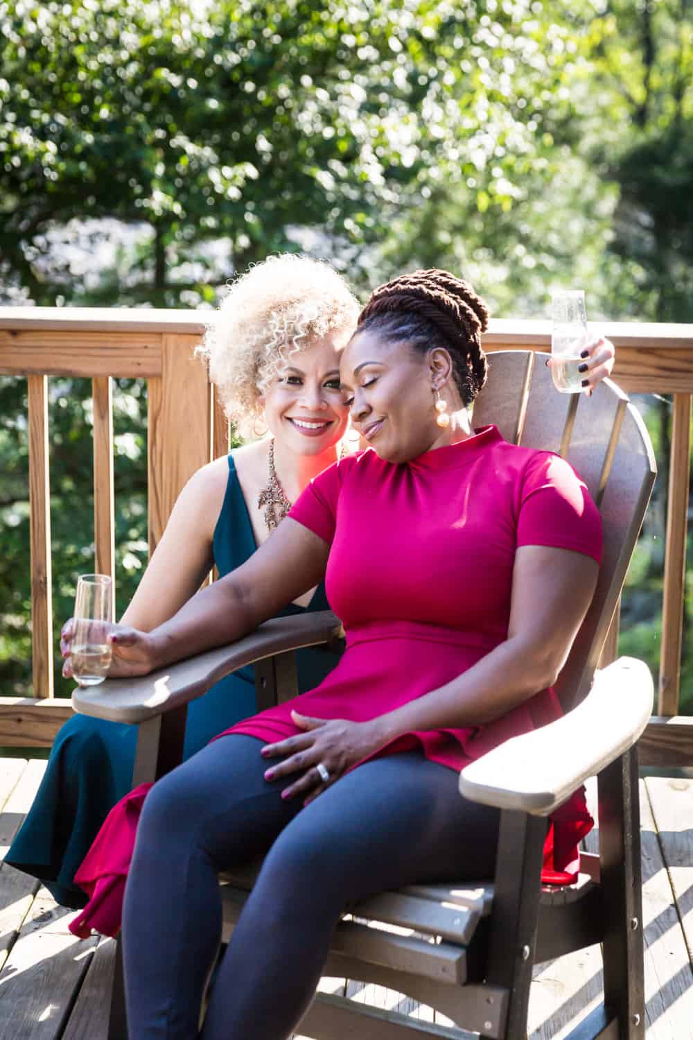 Two women cuddling on porch during a family reunion portrait