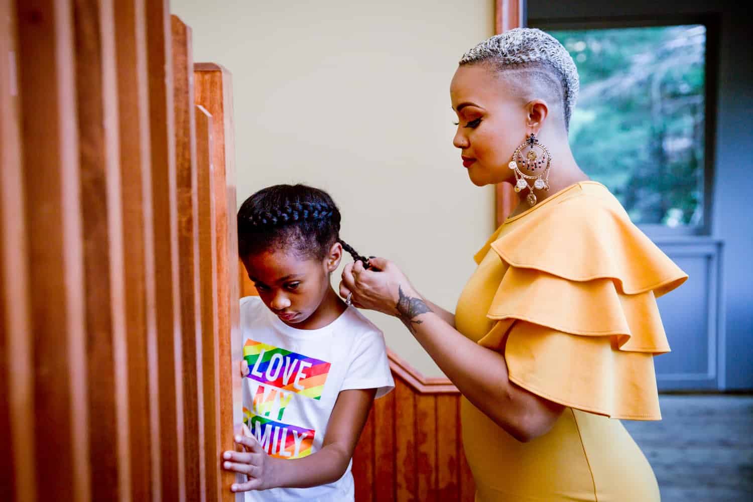 African American mother braiding little girl's hair during a family reunion portrait