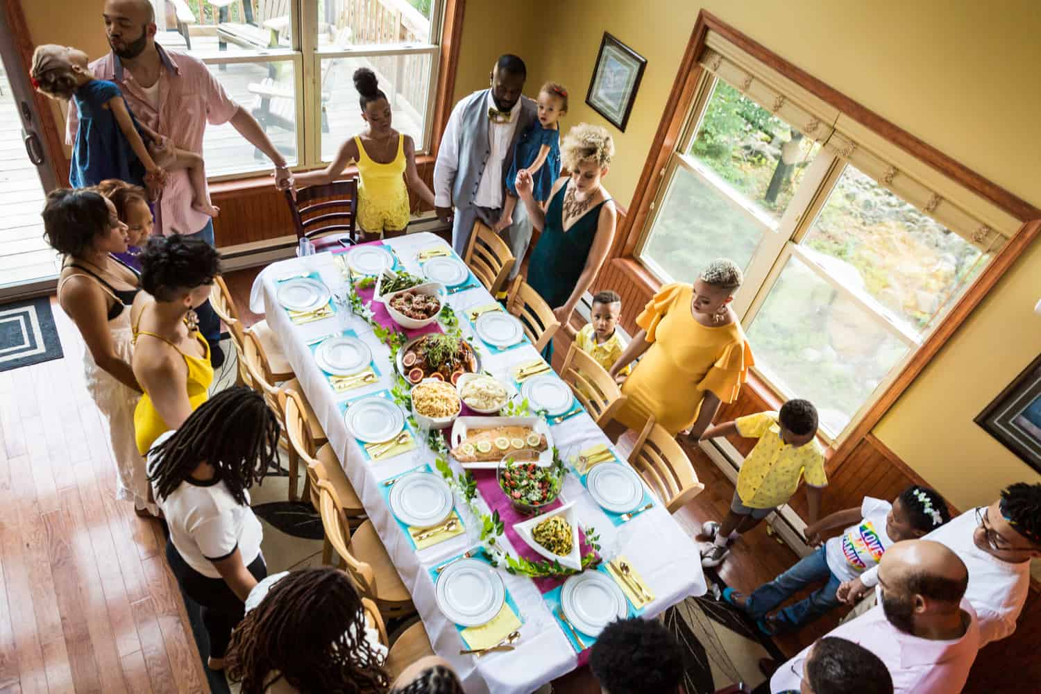 Family holding hands and praying around dinner table during a family reunion portrait