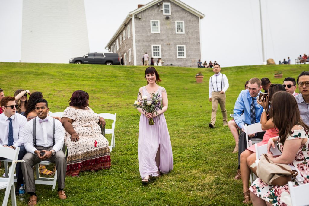 Bridesmaid walking down the aisle for an article on Montauk Lighthouse wedding tips