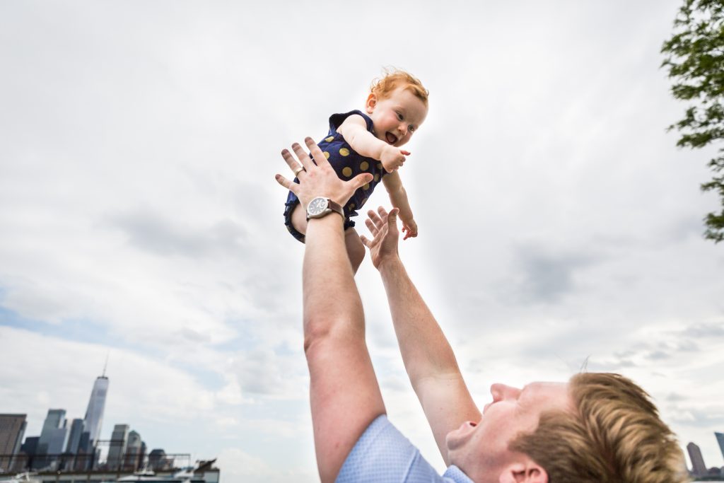 Dad throwing baby in the air in a Hudson River Park Family Portrait