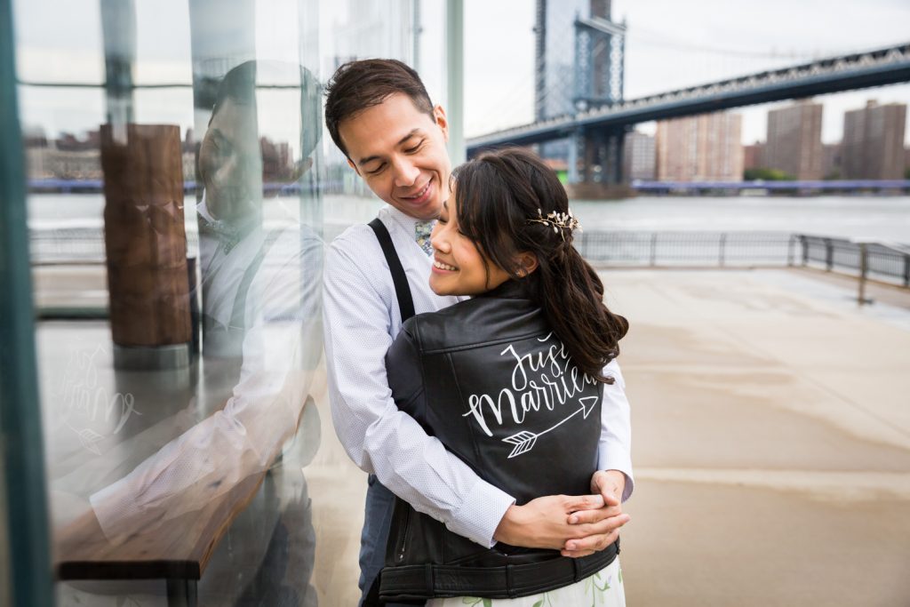 Groom hugging bride wearing 'just married' leather jacket