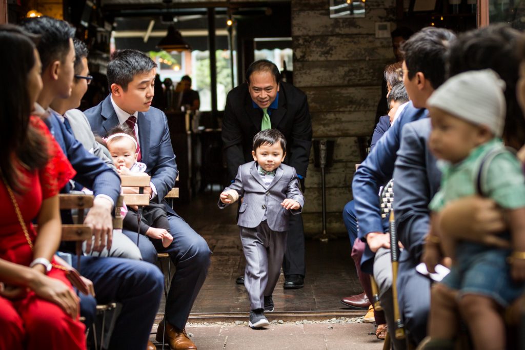 Little ring bearer running down aisle during wedding ceremony