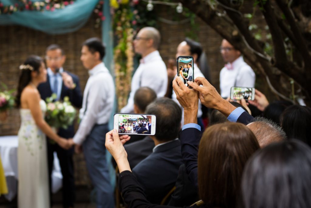 Guests taking photos of wedding ceremony with cell phones
