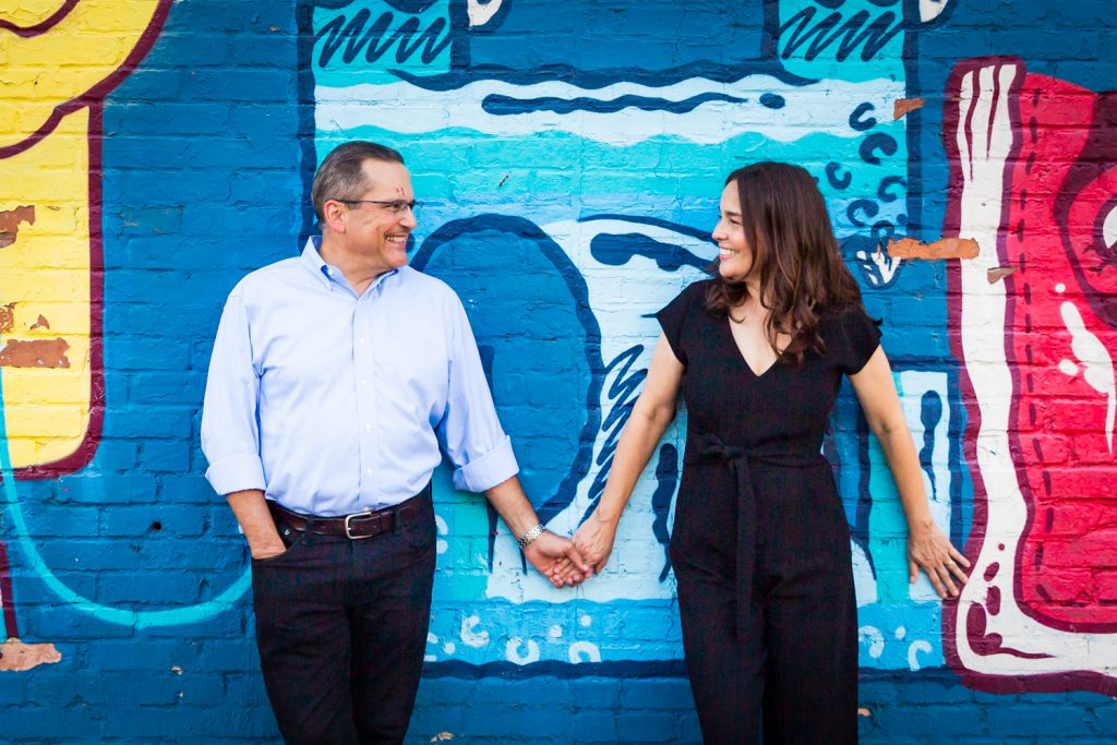 Couple standing against colorful mural in East Village