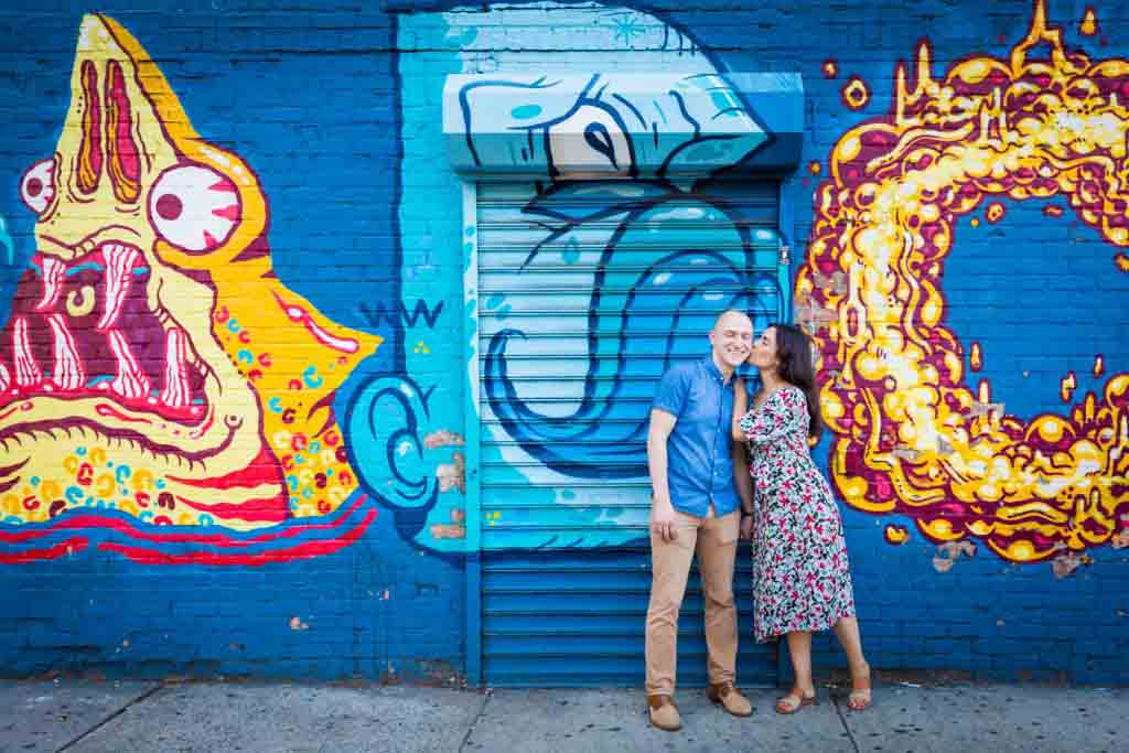 Couple kissing against colorful mural in East Village
