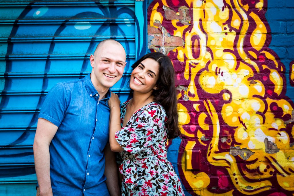 Couple standing against colorful mural in East Village