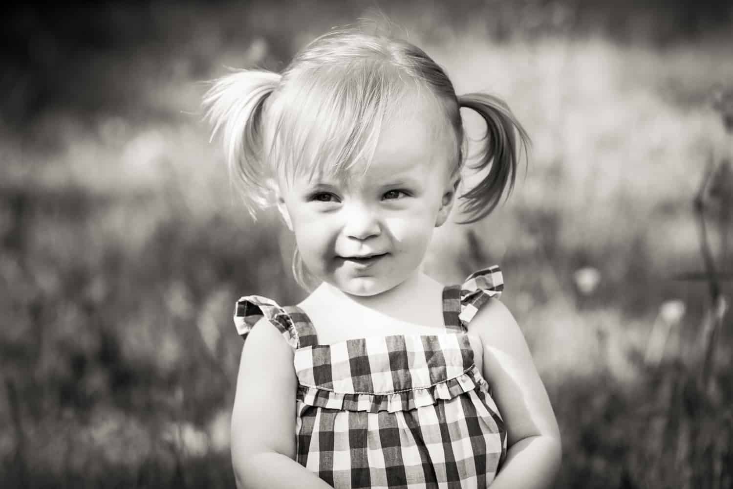Black and white photo of little girl wearing checked dress