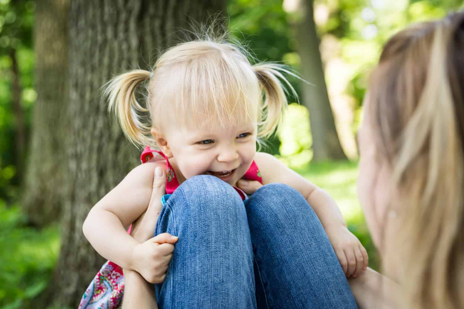 Little girl laying on mother's knees during a Forest Park family photo shoot
