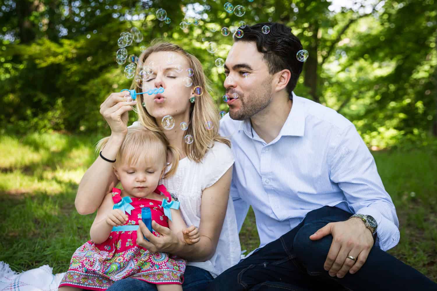 Parents and little girl blowing bubbles during a Forest Park family photo shoot