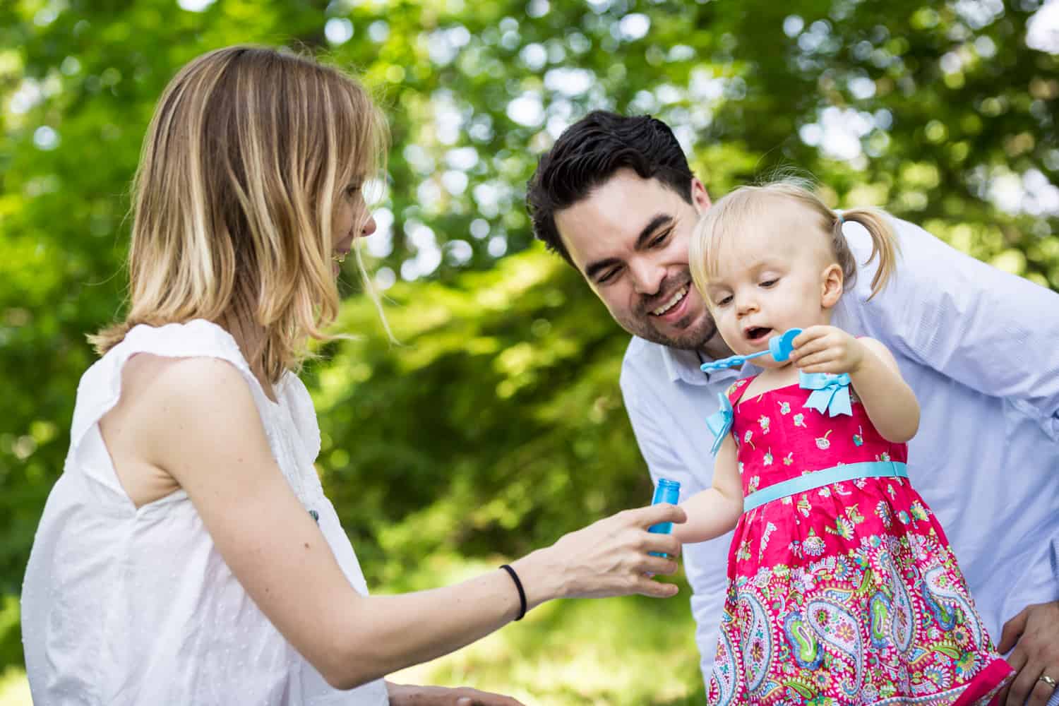 Parents blowing bubbles with little girl during a Forest Park family photo shoot