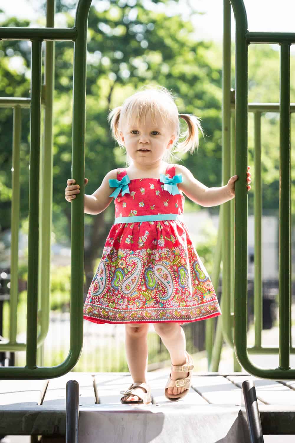 Little girl standing on slide in sunlight during a Forest Park family photo shoot