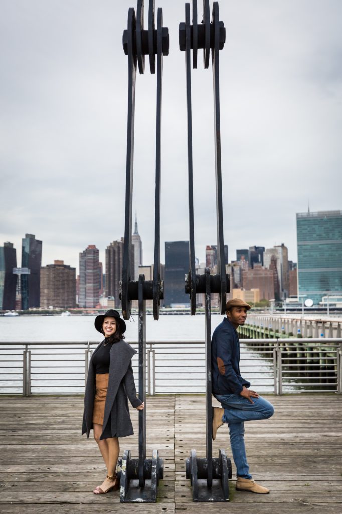 Couple standing beside dock equipment in Long Island City engagement shoot