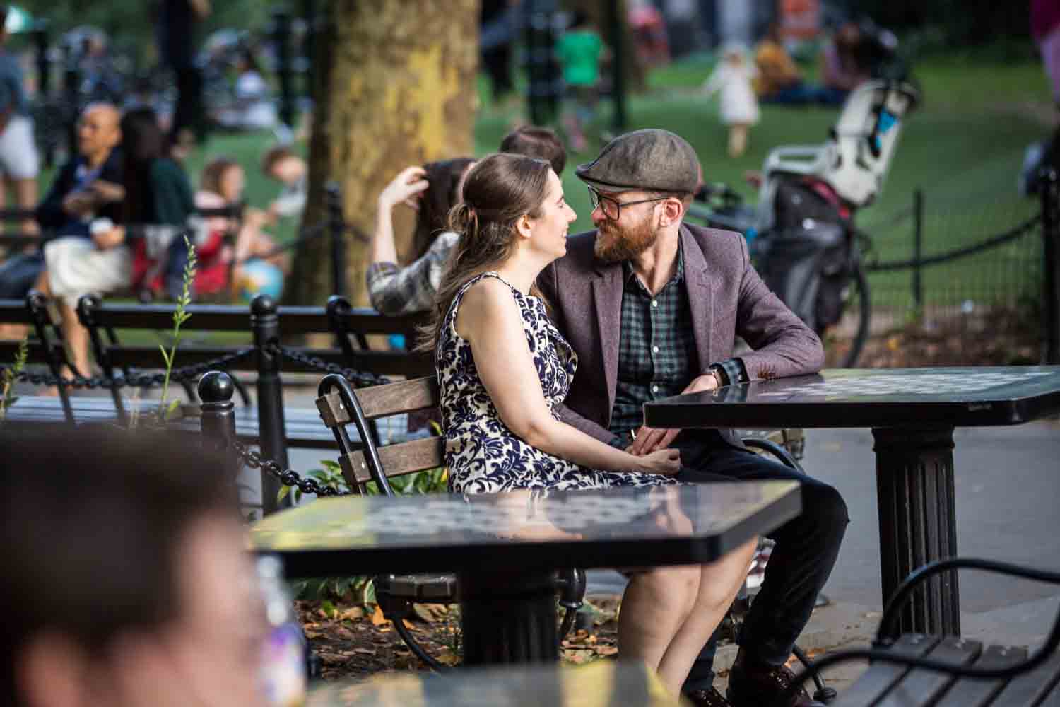Couple sitting at chess table in Washington Square Park for a Greenwich Village engagement portrait