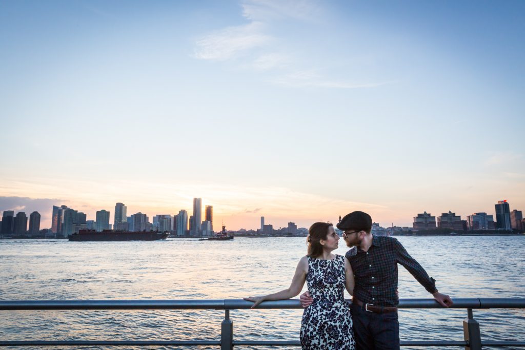 Couple leaning against railing with Hudson River at sunset in background