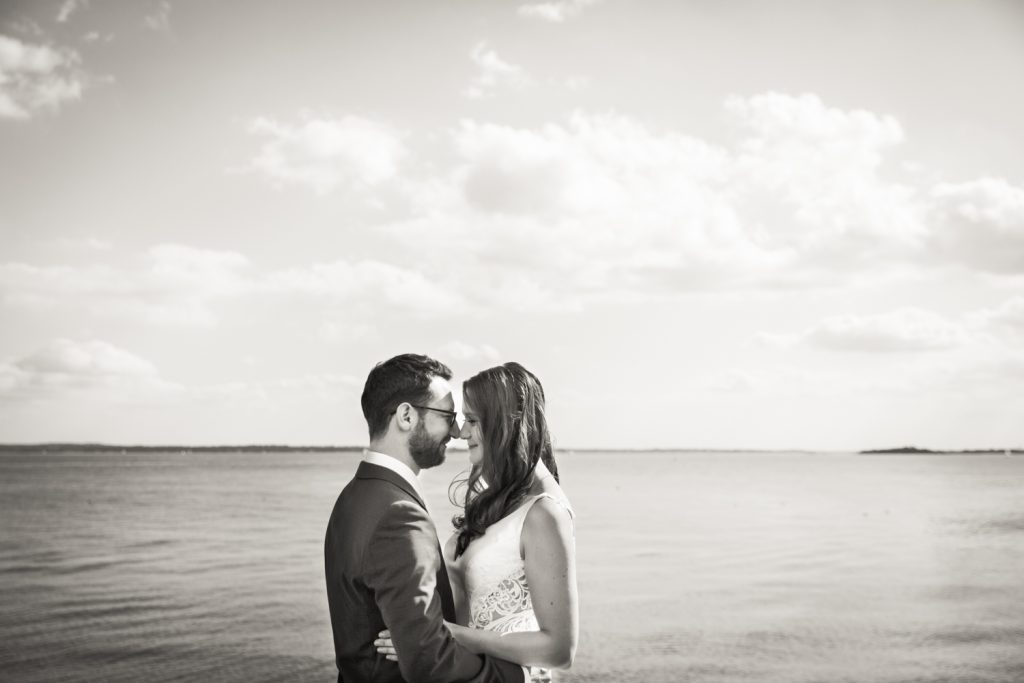 Black and white photo of bride and groom in front of water