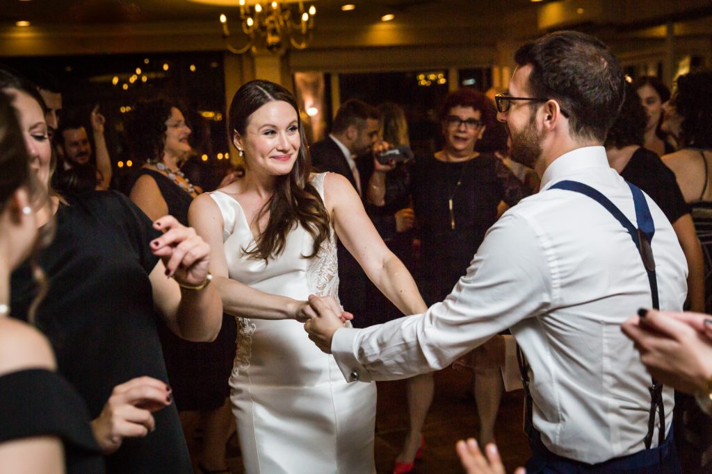 Bride and groom holding hands and dancing at Larchmont Shore Club wedding reception