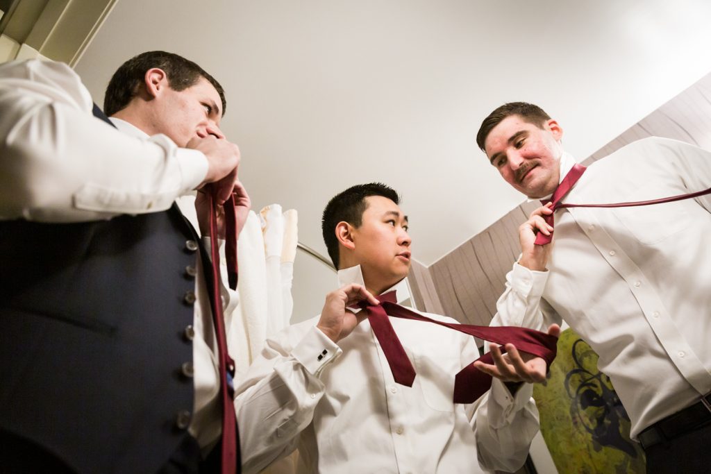 Groom and groomsmen putting on ties at a Westbury Manor wedding