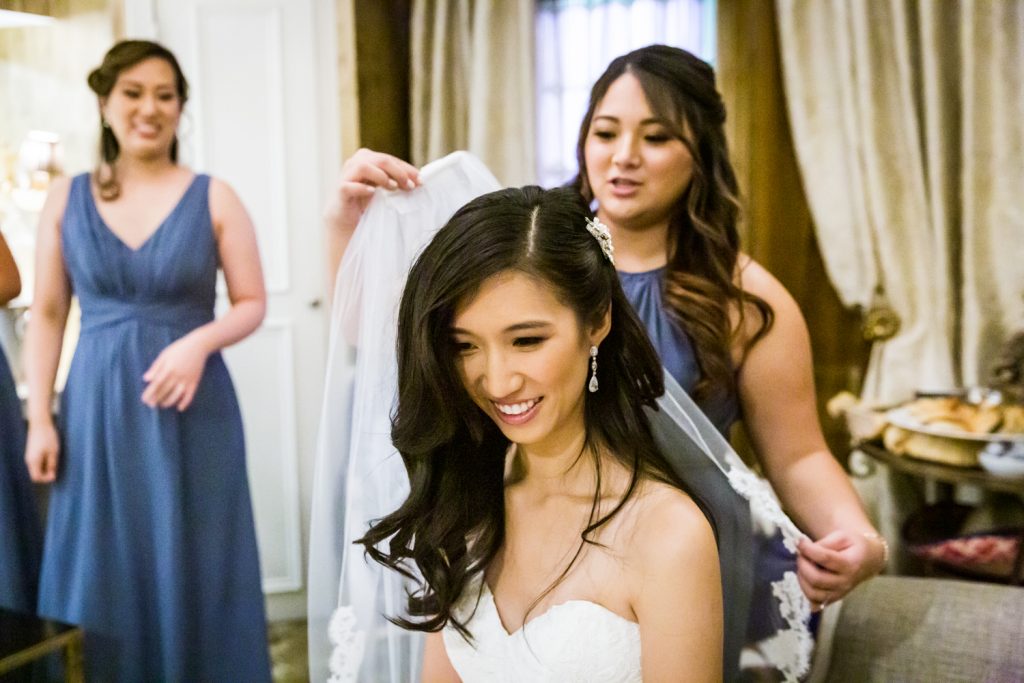 Bridesmaid attaching veil to bride's hair at a Westbury Manor wedding