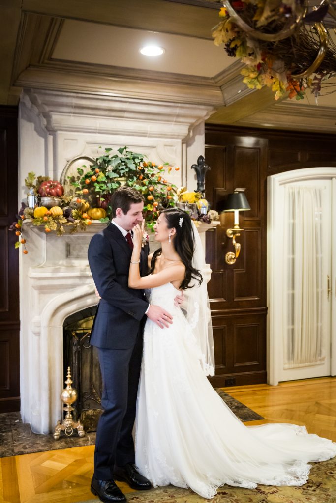 Bride touching groom's nose in front of fireplace