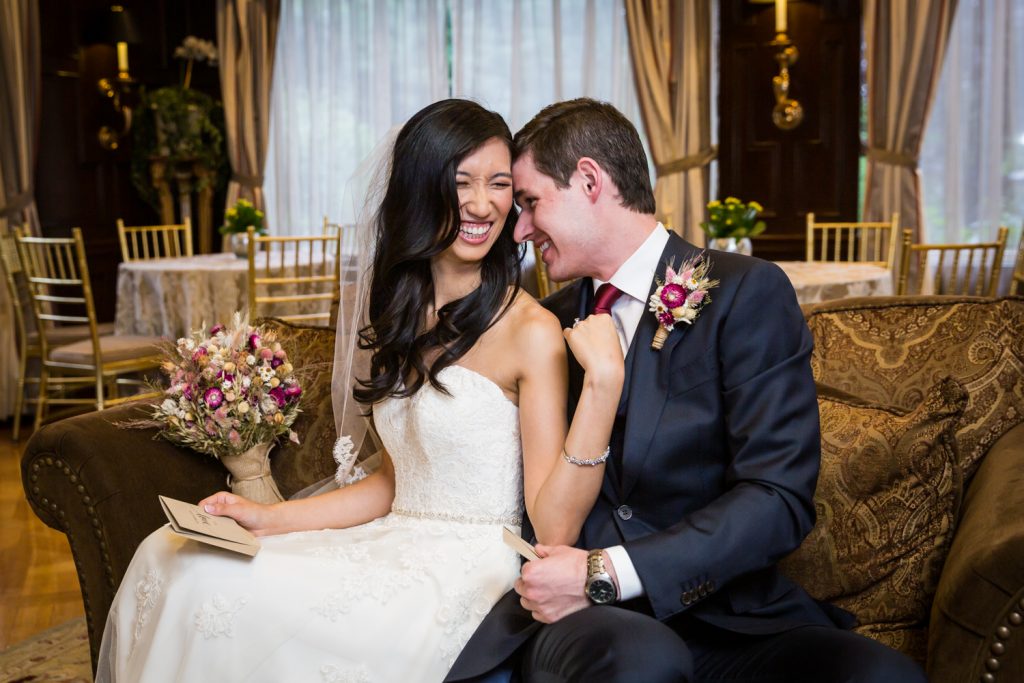 Bride and groom laughing together on couch at a Westbury Manor wedding
