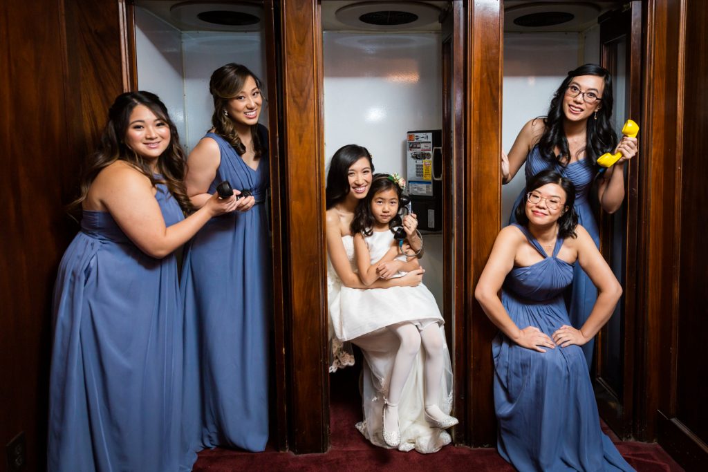 Bride and bridesmaids in old fashioned phone booth at a Westbury Manor wedding