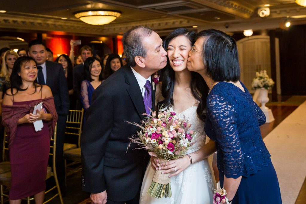 Bride being kissed on both cheeks during ceremony at a Westbury Manor wedding