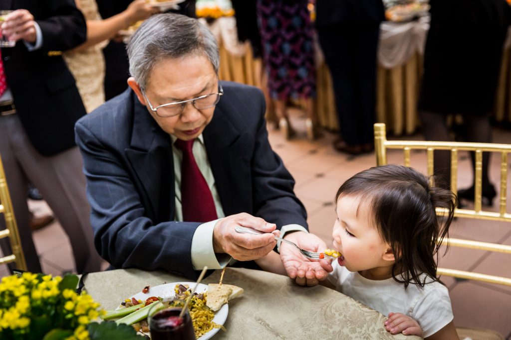 Older man feeding corn to a little girl