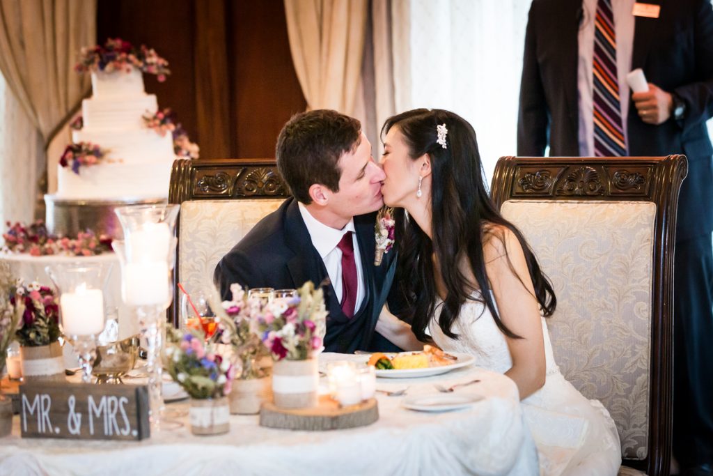 Bride and groom kissing at sweetheart table