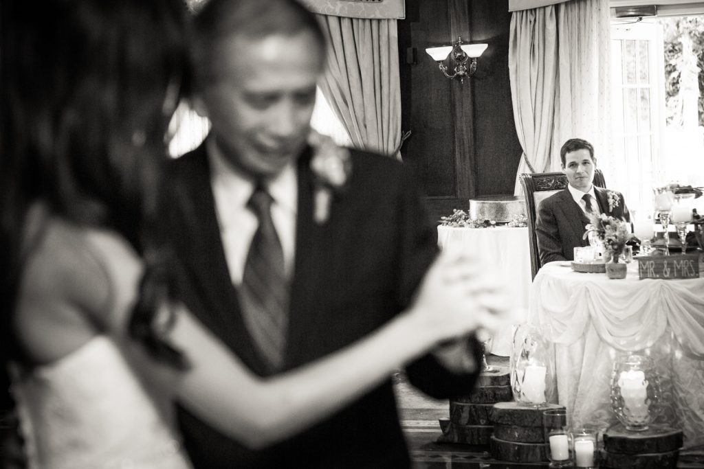Black and white photo of groom watching bride dance with father