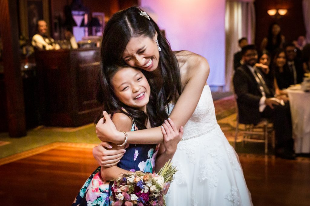 Bride hugging little girl holding bridal bouquet