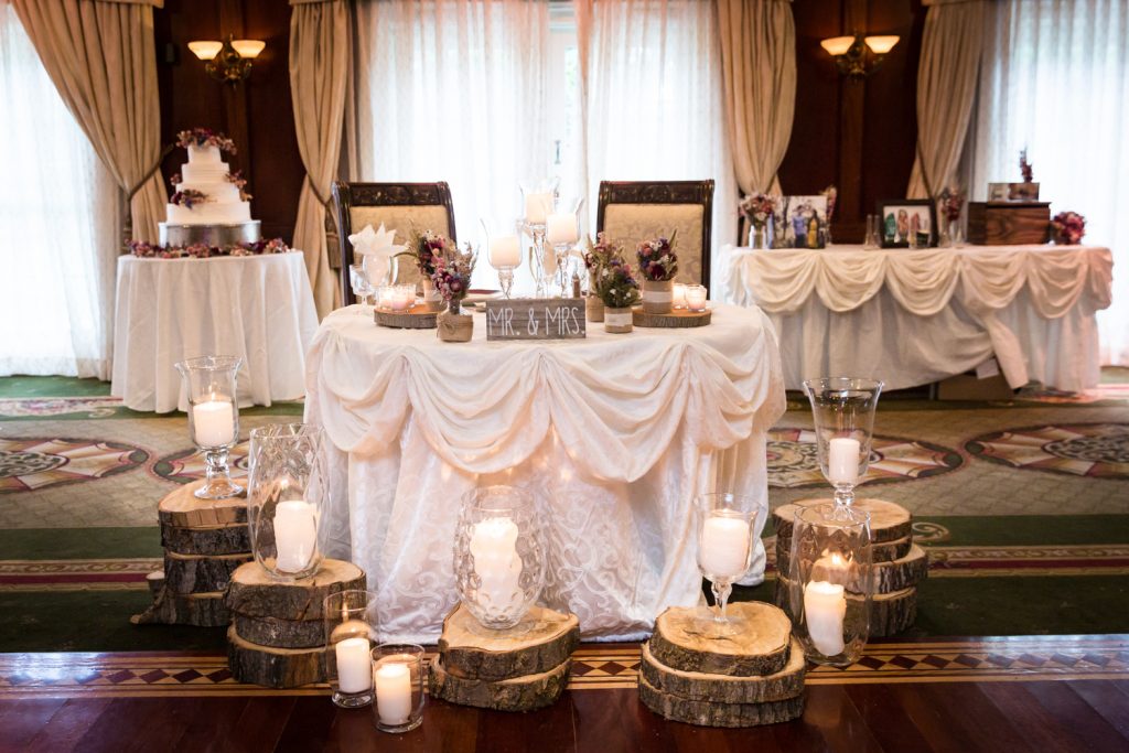 Three tables with wood pillars and candles at a Westbury Manor wedding