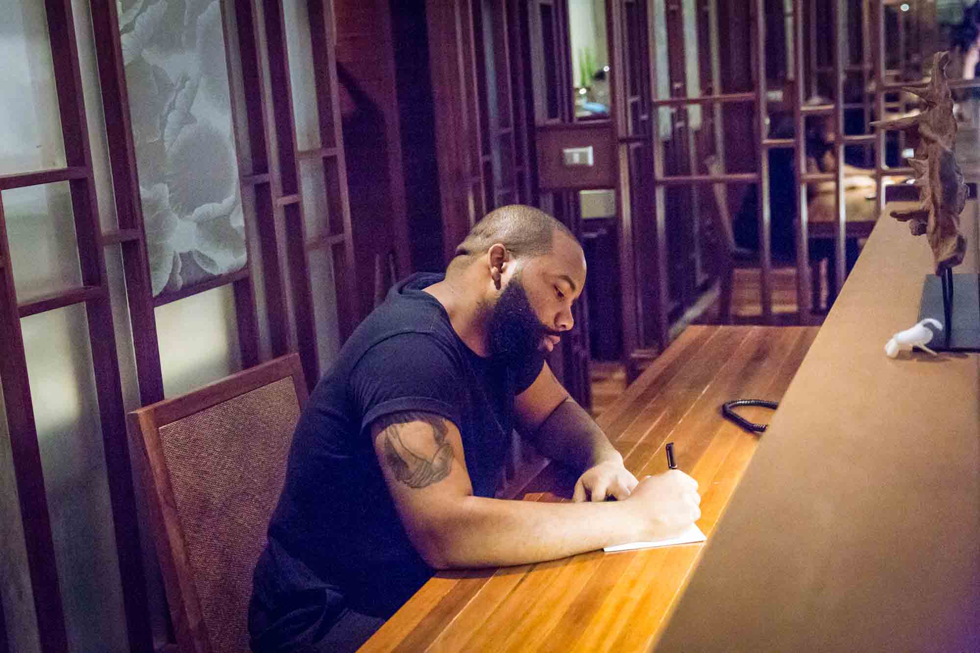 Groom at desk writing letter for an article on destination wedding planning tips