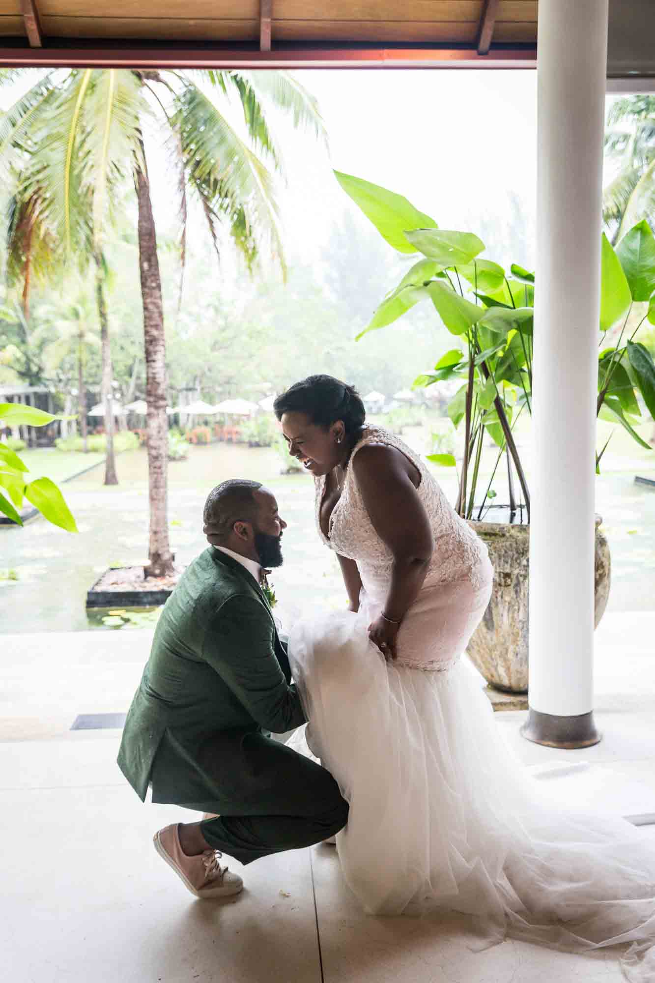 Groom adjusting bride's dress for an article on destination wedding planning tips