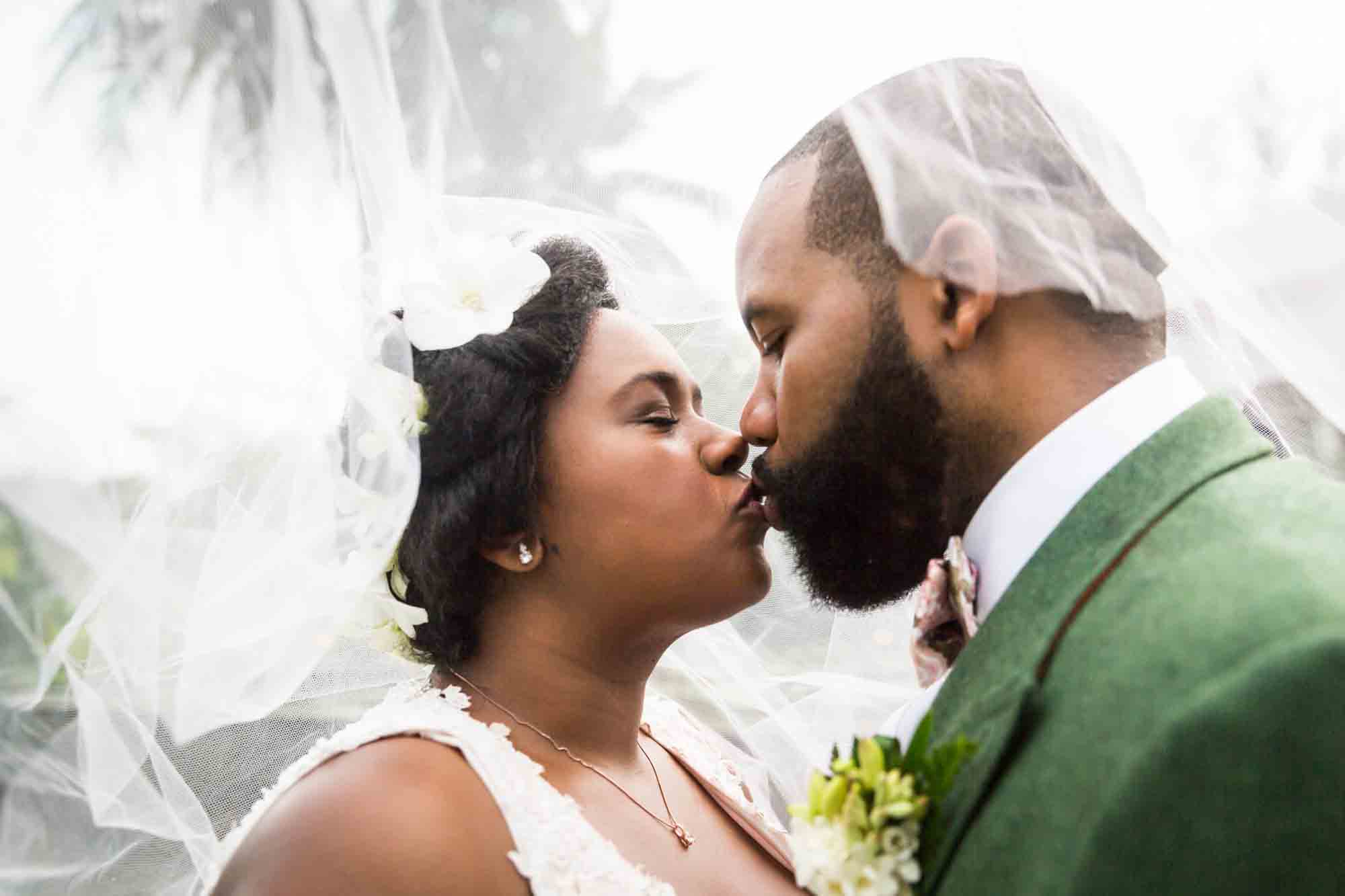 Bride and groom kissing under veil for an article on destination wedding planning tips