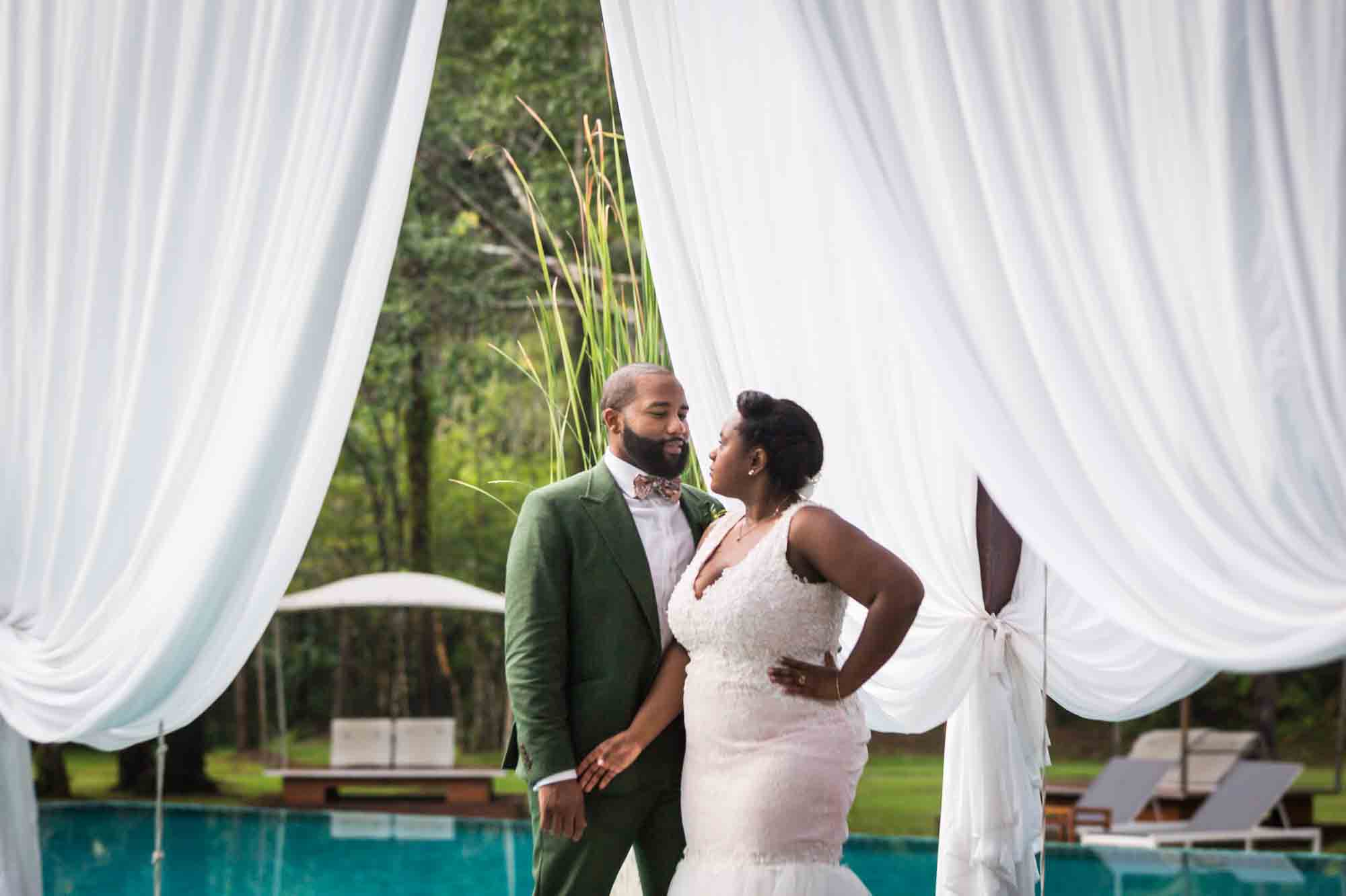 Bride and groom posed by pool for an article on destination wedding planning tips