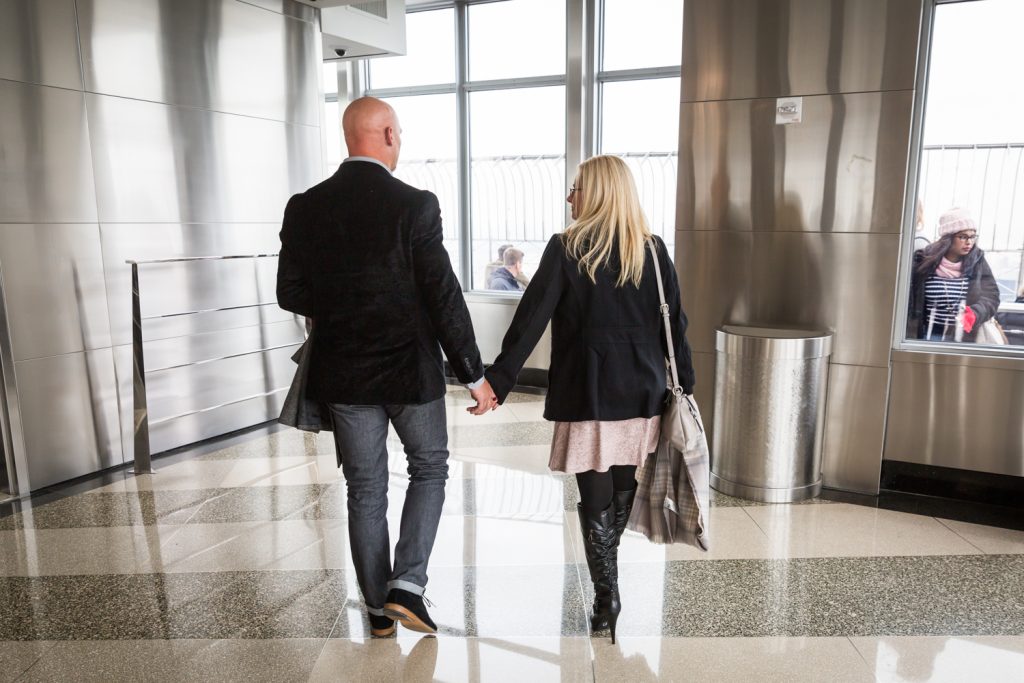 Couple holding hands and walking in lobby of Empire State Building for an article on how to propose on top of the Empire State Building