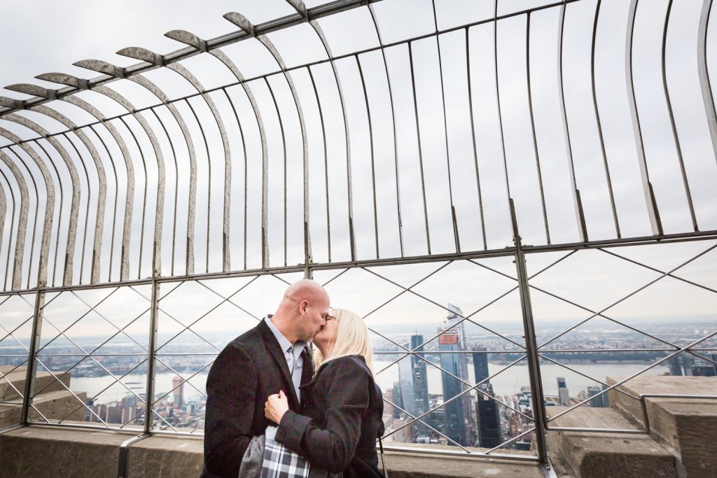 Couple kissing under fencing for an article on how to propose on top of the Empire State Building