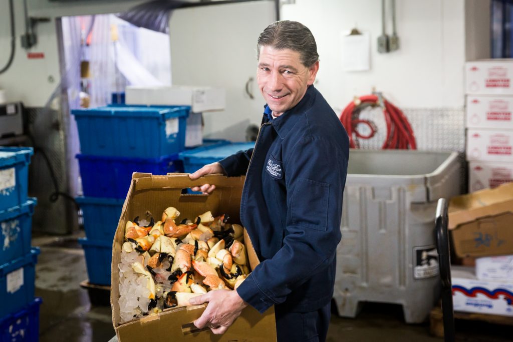 Man holding box of stone crab claws for an article on website photography tips