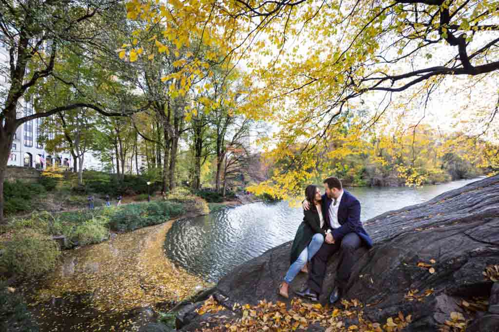 Couple sitting on a rock surrounded by yellow leaves for an article on winter portrait tips