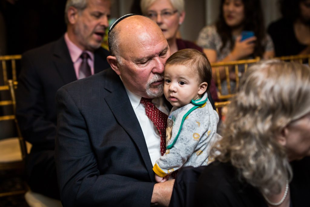 Grandfather holding little grandson at Jewish wedding ceremony