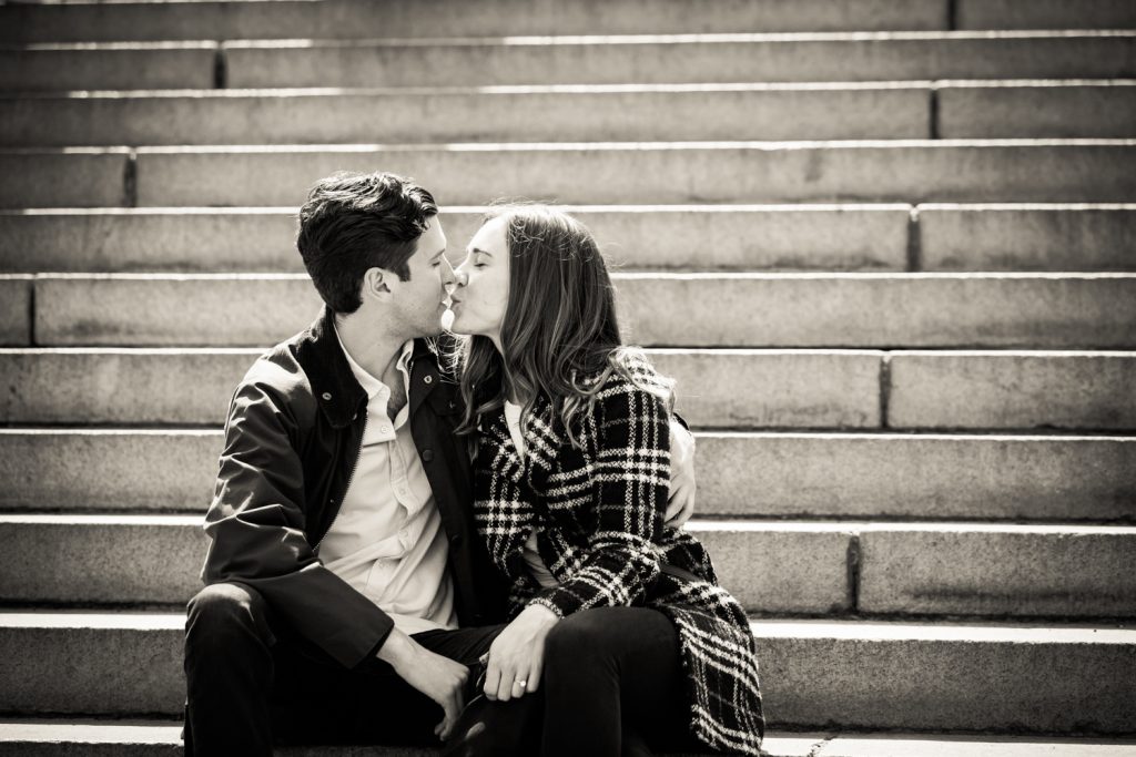 Black and white photo of couple kissing on steps of Bethesda Fountain