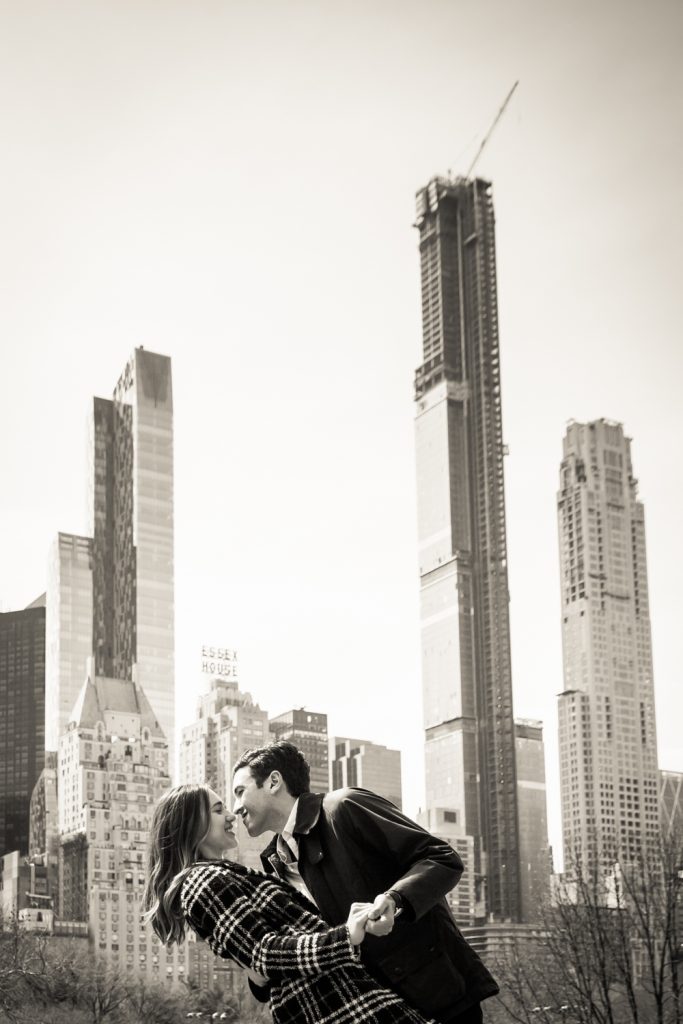 Black and white photo of man dipping woman with NYC skyline in background