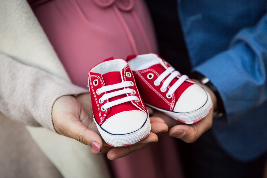 Hands holding baby shoes for an article on maternity portrait tips
